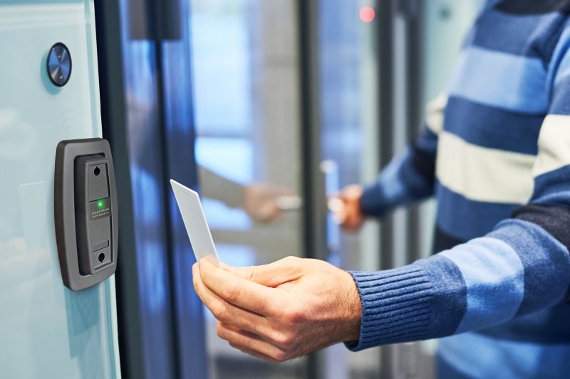Professional using a Hartmann proximity tag at a wall-mounted entry reader